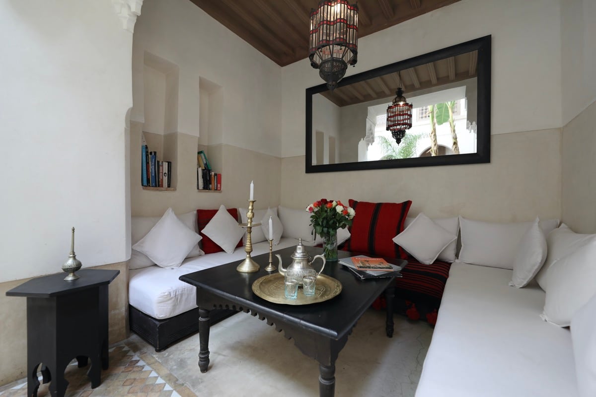 A white salon with red cushions, flowers and a tea tray